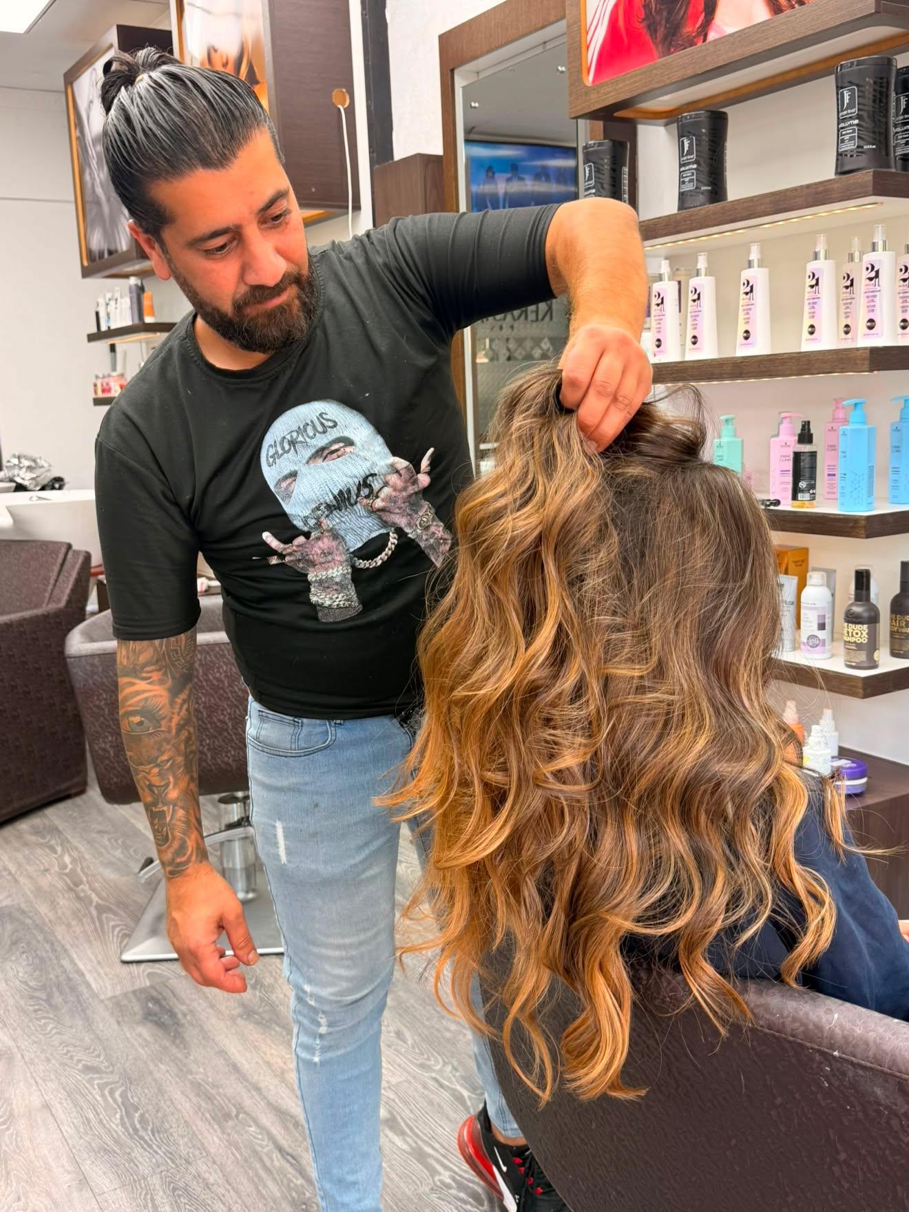 Frisör visar långt vågigt hår med varm balayage-färg
